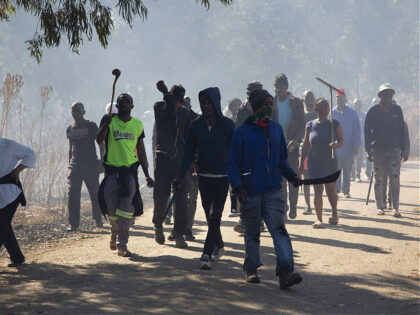 Local residents comb the neighbourhood in search of illegal miners in West Village, Krugersdorp, South Africa Friday Aug. 5, 2022. Community members converged on the neighbourhood in search of illegal miners following the alleged gang rapes of eight women by miners last week. (AP Photo/Denis Farrell)