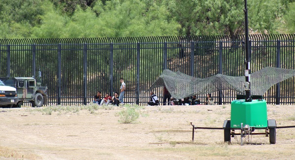 Migrants seek shade near the RIo Grande as temperatures exceed 100 degrees around noon on August 14. (Randy Clark/Breitbart Texas)