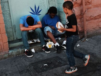 NEW YORK, NY - AUGUST 28: A child walks by two men who are high on K2 or 'Spice', a synthetic marijuana drug, along a street in East Harlem on August 28, 2015 in New York City. New York, along with other cities, is experiencing a deadly epidemic of synthetic …