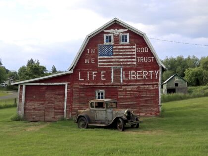 The national motto of the United States, “In God We Trust” is seen painted on a barn w