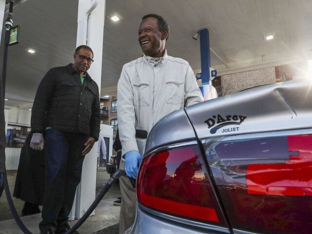 Chicago mayoral candidate Willie Wilson laughs with supporters while pumping gas on April