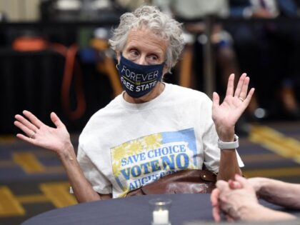 Jeri Swinton wears a mask reading "Forever the Free State" as she talks to friends during the pro-choice Kansas for Constitutional Freedom primary election watch party in Overland Park, Kansas August 2, 2022. Voters headed to the polls in the Midwestern state of Kansas Tuesday to weigh in on the …