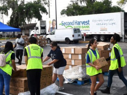 ORLANDO, FLORIDA, UNITED STATES - 2022/06/25: Volunteers move boxes of food for the needy at a food distribution event sponsored by the Second Harvest Food Bank of Central Florida and Orange County at St. John Vianney Church in Orlando, Florida. High food and gas prices are squeezing working families, sending …