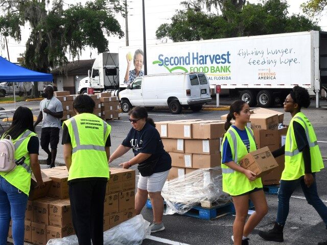 ORLANDO, FLORIDA, UNITED STATES - 2022/06/25: Volunteers move boxes of food for the needy at a food distribution event sponsored by the Second Harvest Food Bank of Central Florida and Orange County at St. John Vianney Church in Orlando, Florida. High food and gas prices are squeezing working families, sending …