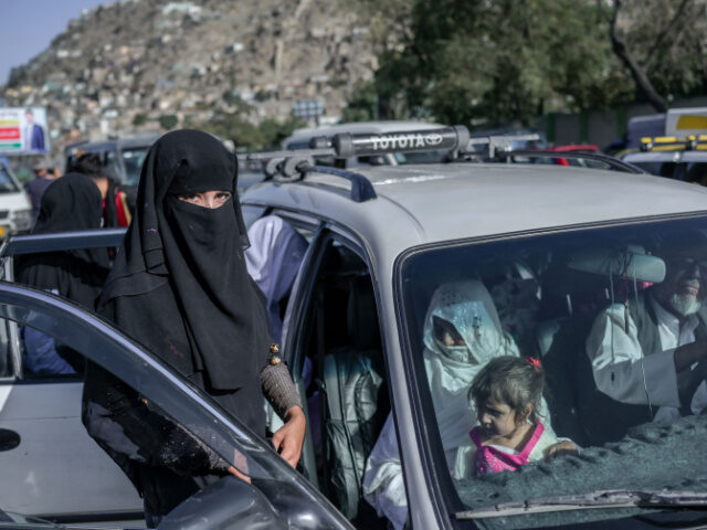 A woman gets into a car parked along the roadside in Kabul on September 13, 2021. (Photo b