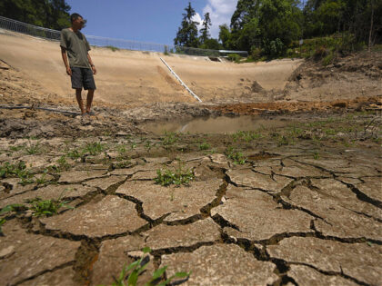 Gan Bingdong stands in the basin of a community reservoir near his farm that ran nearly empty after its retaining wall started to leak and hot weather and drought conditions accelerated the loss of water, in Longquan village in southwestern China's Chongqing Municipality, Saturday, Aug. 20, 2022. Drought conditions across …
