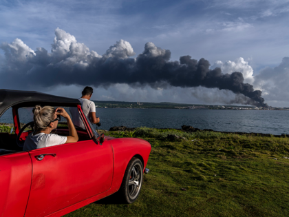 People watch a huge plume of smoke rise from the Matanzas supertanker base, as firefighter