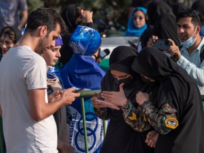 Two Iranian policewomen check a soccer ticket on a soccer female fans smartphone as she wa