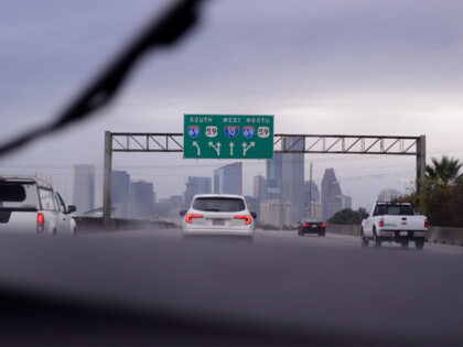 Inside The Car View Of Highway With Traffic During A Rain Storm Heading Into An Urban Skyline - stock photo