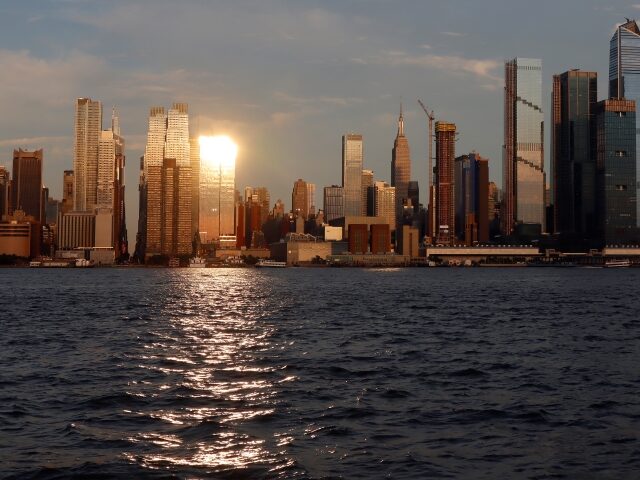 WEEHAWKEN, NJ - JULY 9: A seagull flies over Hudson Yards as the sun sets on the skyline o