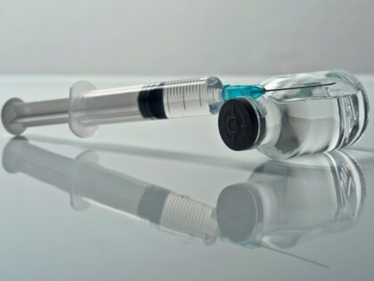 Injectable medications in sealed vials and a disposable plastic medical syringe against gray background.Studio shot