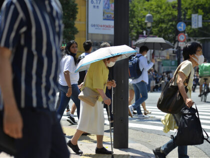 TOKYO, JAPAN - JUNE 27: An old person walks on the street using an umbrella to protect herself from the sun on June 27, 2022, in Tokyo's popular Shibuya district in Tokyo, Japan. The capital of Japan has been swept by a heat wave for the past few days with …