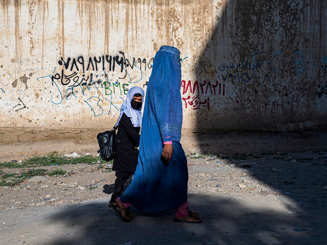 In this picture taken on August 9, 2022, an Afghan woman and a girl walk to a primary scho