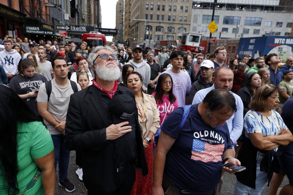 People gather on Cedar Street by the perimeter of the commemoration ceremony during a moment of silence on the 21st anniversary of the September 11, 2001 terror attacks on Sunday, Sept. 11, 2022 in New York. (AP Photo/Stefan Jeremiah)