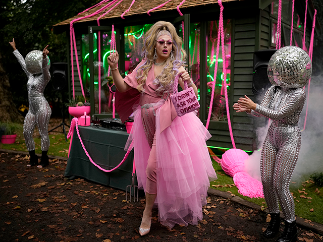 Daisy the Drag Queen Gardener dances next to performers wearing disco ball heads by the "T