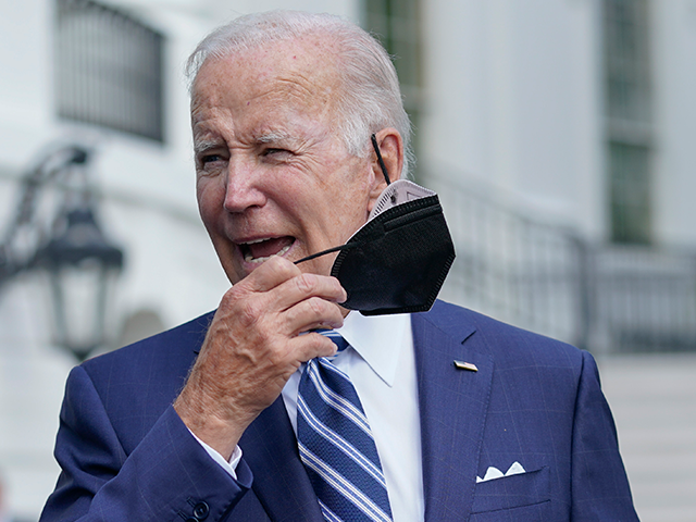 President Joe Biden removes his face mask as he walks to speak to members of the media bef
