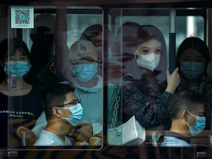 Commuters wearing face masks ride on a crowded bus traveling from the outskirts of the cap