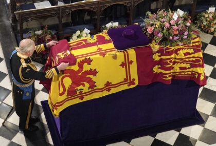King Charles III places the Queen's Company Camp Colour of the Grenadier Guards on the coffin at the Committal Service for Queen Elizabeth II, held at St George's Chapel in Windsor Castle, Monday Sept. 19, 2022. (Jonathan Brady/Pool Photo via AP)