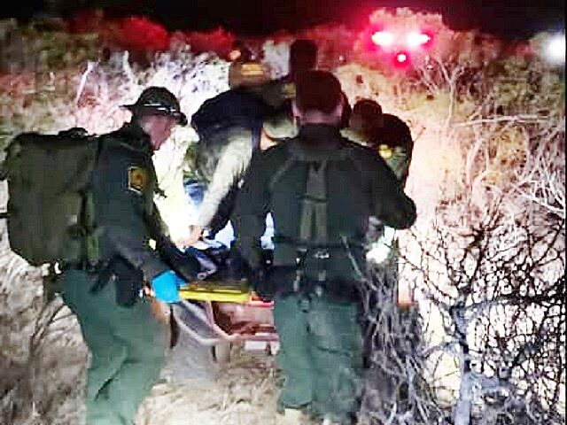 Border Patrol agents carry a migrant from the scene of a crash were at least one died afte