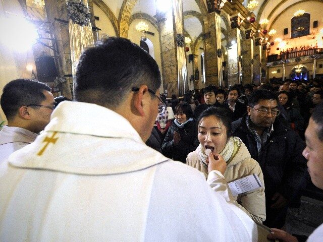 Chinese worshippers receive the Eucharist from a priest as they attend Christmas Eve mass