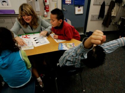 Fernando Lugo stretches while Reading specialist Alice Howard helps Eduardo Farias,R with a reading exercise during a Tier 2, 1st grade class at Lilian J. Rice Elementary in Chula Vista, CA. Rice is the head of a Response to Intervention Class which hepls english learners become profiicient in reading.(Photo by …