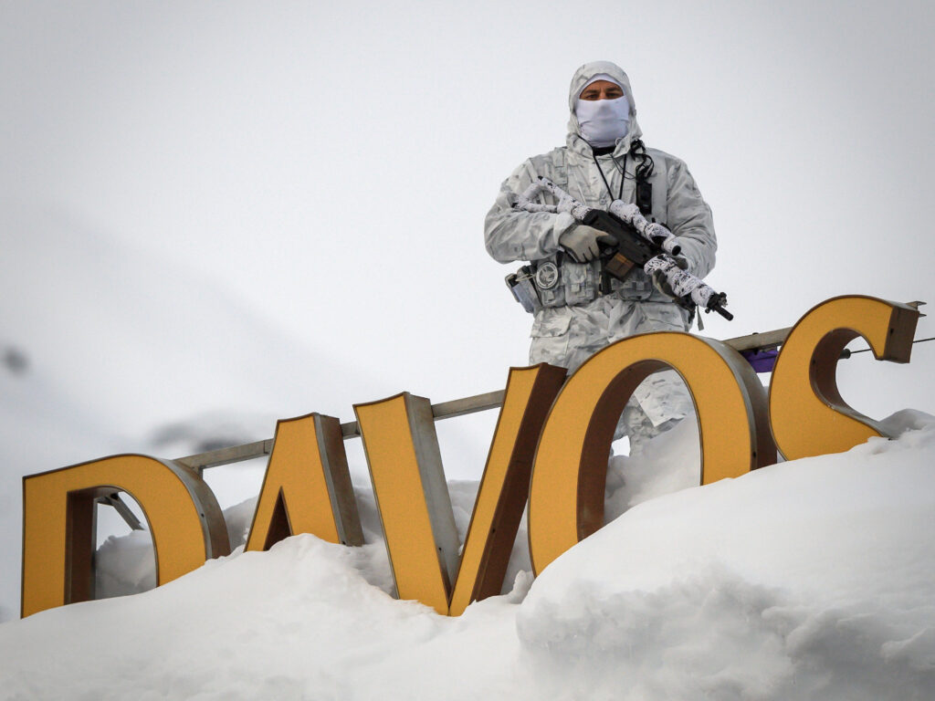 A policeman wearing camouflage clothing stands on the rooftop of a hotel, next to letters covered in snow reading 'Davos', near the Congress Centre ahead of the World Economic Forum (WEF) annual meeting on January 21, 2019 in Davos, eastern Switzerland. (Photo by Fabrice COFFRINI / AFP) (Photo credit should read FABRICE COFFRINI/AFP via Getty Images)