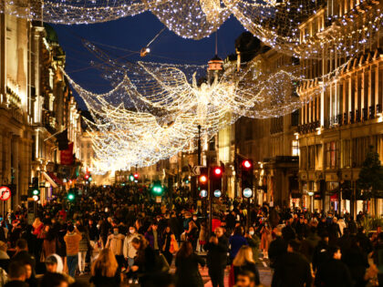 Shoppers, some wearing face masks, walk under Christmas lights on a temporarily-pedestrianised Regent Street in London, England, on December 19, 2020.