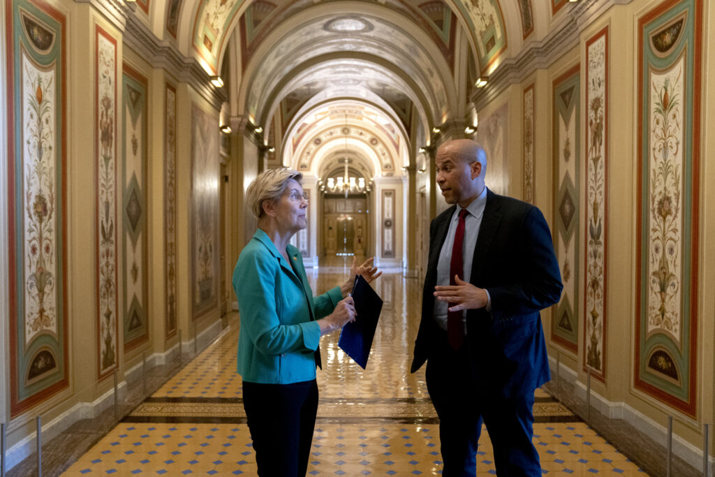 Senator Elizabeth Warren, a Democrat from Massachusetts, left, speaks to Senator Cory Booker, a Democrat from New Jersey, at the U.S. Capitol in Washington, D.C., U.S., on Wednesday, June 23, 2021. Senators negotiating a bipartisan infrastructure plan with the White House will meet Thursday with President Joe Biden to present an outline for a roughly $579 billion compromise package of spending on roads, bridges and other projects. Photographer: Stefani Reynolds/Bloomberg via Getty Images