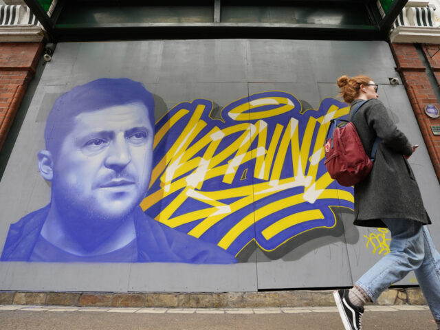 People pass a mural of President of Ukraine Volodymyr Zelenskyy, by the artist Aches, in c