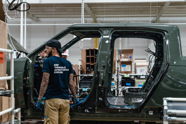 Workers assembly components of a Rivian R1T electric vehicle (EV) pickup truck at the comp