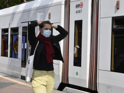 26 May 2022, North Rhine-Westphalia, Cologne: A citizen wears mouth-to-nose protection in front of a streetcar. The new Corona Protection Ordinance that came into force today is the old one: It was not changed and simply extended. Thus, nothing changes in the measures. And the mask obligation in the public …