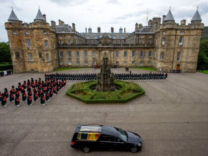 TOPSHOT - The hearse carrying the coffin of the late Queen Elizabeth II, draped with the Royal Standard of Scotland, arrives at the Palace of Holyroodhouse, in Edinburgh on September 11, 2022. - Queen Elizabeth II's coffin will travel by road through Scottish towns and villages on Sunday as it …