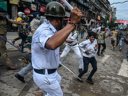 Policemen wield their batons against a supporter of India's ruling Bharatiya Janata Party