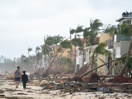 People walk along the beach looking at property damaged by Hurricane Ian on September 29,