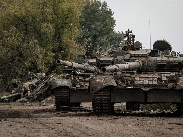 Ukrainian soldiers (L) scavenge an abandoned Russian T-90A tank in Kyrylivka, in the recen
