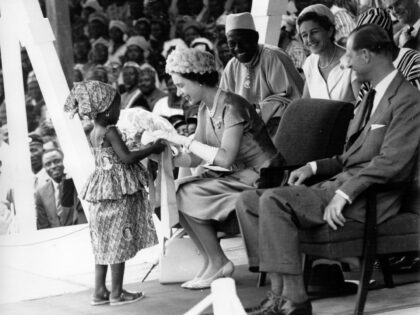 30th November 1961: HM Queen Elizabeth II receiving a bouquet from a small native girl, watched by the Duke of Edinburgh and others, during the Royal Tour of Sierra Leone. (Photo by Hulton Archive/Getty Images)
