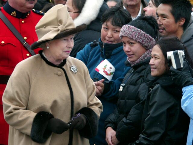 IQALUIT, CANADA: Queen Elizabeth II (L) walks past Inuit while on a walk-about after arri
