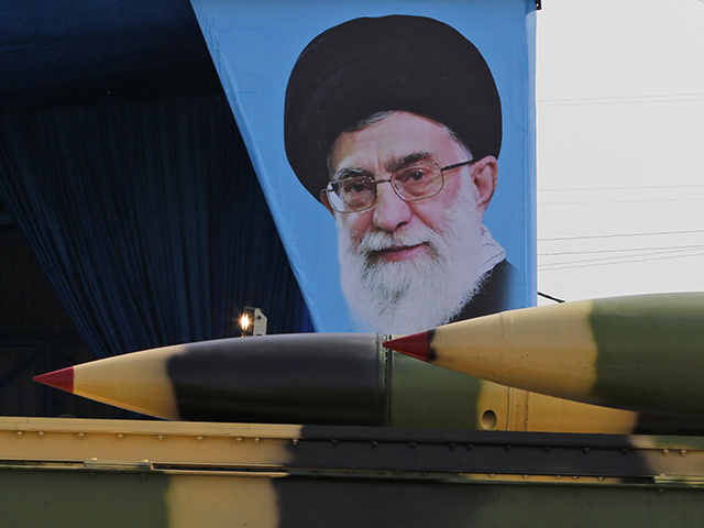 An Iranian military truck carries surface-to-air missiles past a portrait of Iran's Suprem