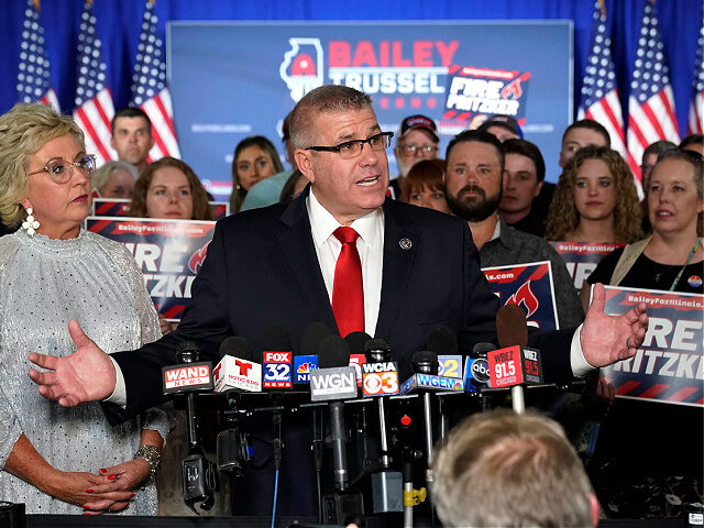 Republican gubernatorial primary candidate Darren Bailey, center, stands with his wife, Cindy Stortzum, and responds to reporters' questions after winning the Republican gubernatorial primary, Tuesday, June 28, 2022, in Effingham, Ill. Bailey will now face Democratic Gov. J.B. Pritzker in the fall. (AP Photo/Charles Rex Arbogast)