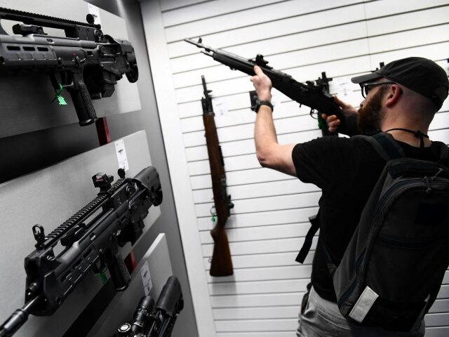 Springfield Armory Hellion bullpup rifles (L) are displayed as an attendee holds an M1A se