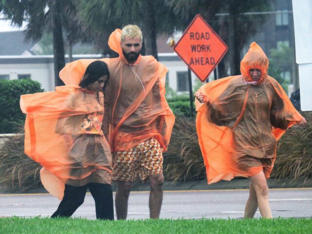 Visitors face strong wind gusts from Hurricane Ian as they walk along International Drive