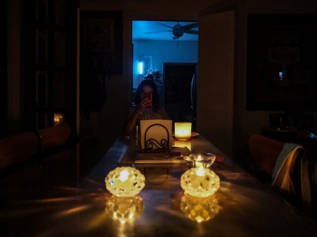 A person sits by candle light in a home in the Condado community of Santurce in San Juan, Puerto Rico, on September 19, 2022, after the the power went out with the passage of Hurricane Fiona. - Hurricane Fiona smashed into Puerto Rico, knocking out the US island territory's power …