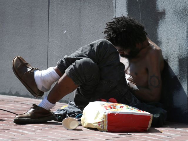 A man sits against a wall at Market and Hyde streets in San Francisco, Calif. on Thursday,