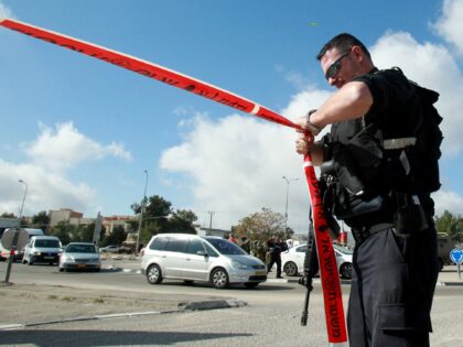 An Israeli police officer holds police tape at an intersection where Amal Jihad Taqatqa, a Palestinian woman from Beit Fajjar near the West Bank city of Bethlehem, attacked an Israeli civilian in the Gush Etzion settlement bloc, south of Bethlehem on December 1,2014. The Israeli army shot and wounded a …