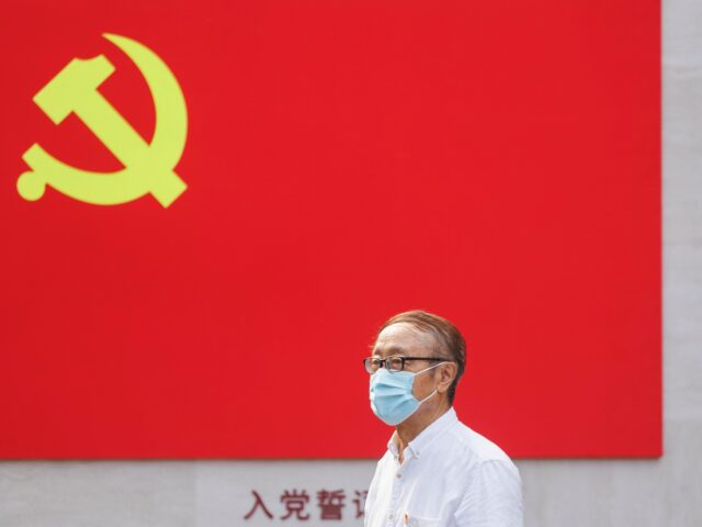 SHANGHAI, CHINA - JULY 01: An old man with protective mask poses for photo under a CCP flag at the memorial hall of the first National Congress of CCP on July 01, 2022 in Shanghai, China. (Photo by Hugo Hu/Getty Images)