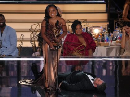 LOS ANGELES, CALIFORNIA - SEPTEMBER 12: (L-R) Quinta Brunson accepts the Outstanding Writing for a Comedy Series award for ‘Abbott Elementary’ from (lying on the stage) onstage during the 74th Primetime Emmys at Microsoft Theater on September 12, 2022 in Los Angeles, California. (Photo by Kevin Mazur/WireImage)