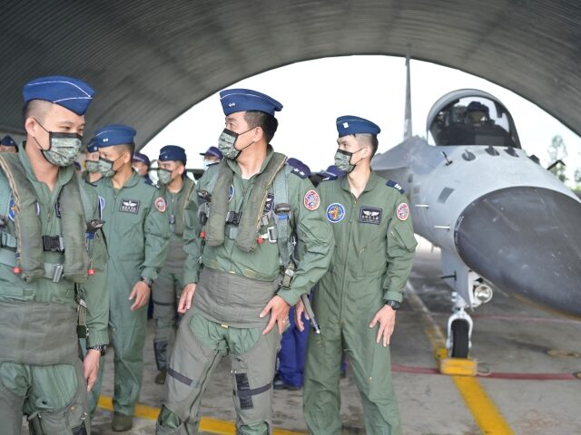 Taiwanese pilots walk pass an Indigenous Defense Fighter (IDF) at an air force base while