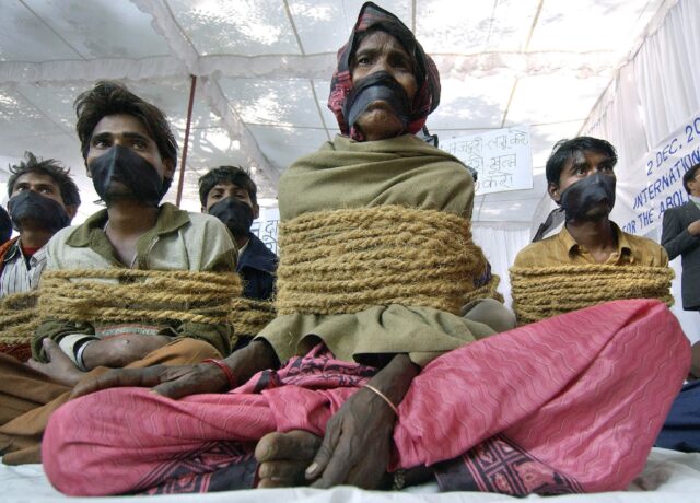 Indian activists pose as bonded labourers with their hands tied up by rope