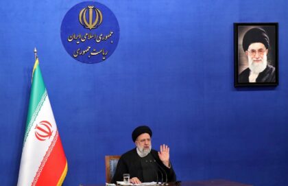 Iranian President Ebrahim Raisi sits near a portrait of Iran's Supreme Leader Ayatollah Al