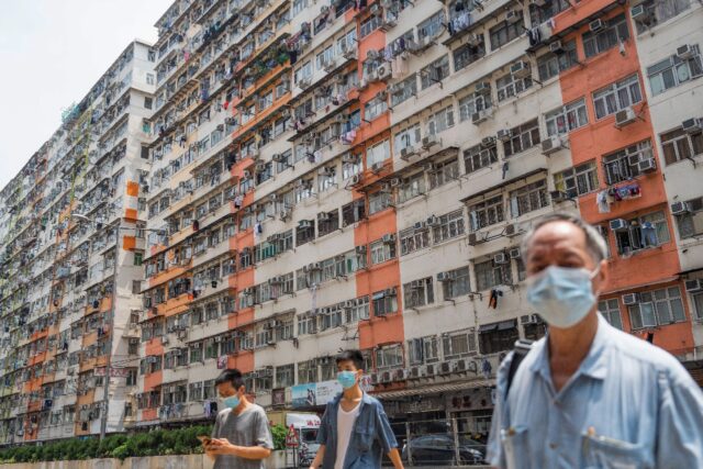 Pedestrians cross a road past apartment blocks in Hong Kong's To Kwa Wan area during inten